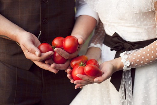 Bride and groom holding tomatoes
