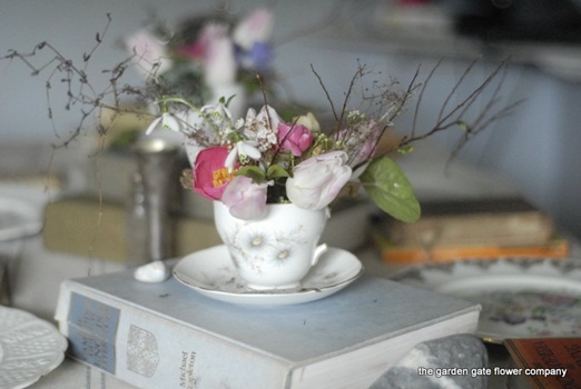 Pink tulips, snowdrops and cyclamen leaves in a vintage teacup