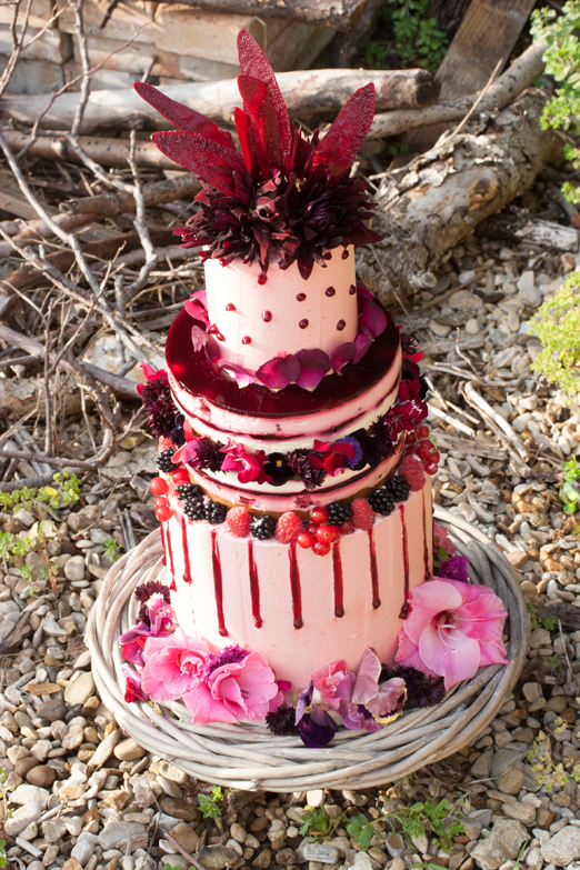Purple and red autumn wedding cake with edible flowers and berries