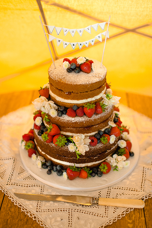 Tiered Victoria sponge wedding cake with mini bunting cake topper – photography http://www.bohemianweddings.co.uk/