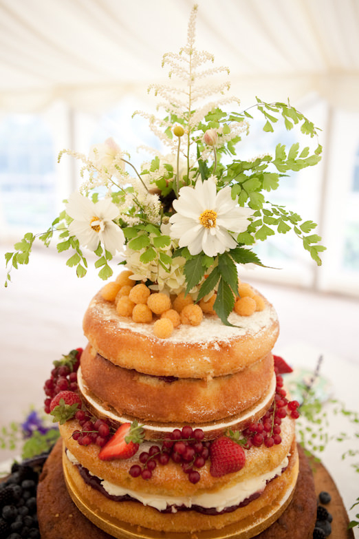 Tiered Victoria sponge wedding cake with flowers, ferns, berries, and yellow raspberries // Photography by Emma Stoner www.emmastonerweddings.com // The Natural Wedding Company
