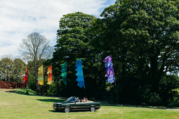 Bride arriving at meadow ceremony in BMW // Bohemian Weddings // The Natural Wedding Company