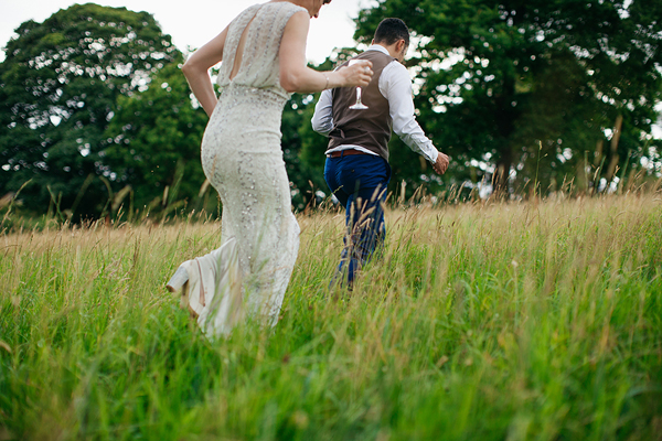 Bride and groom walking through a meadow // Bohemian Weddings // The Natural Wedding Company