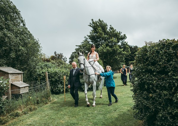 Bride riding a grey horse to her garden tipi wedding // Tracey Warbey Photography // The Natural Wedding Company